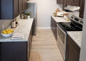 Thumbnail 7 of 10 - A kitchen with dark brown cabinets and a granite countertop.
