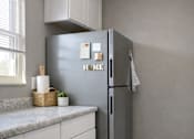 Thumbnail 3 of 14 - A kitchen with a grey fridge and white cabinets.