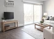 Thumbnail 1 of 10 - A living room with a flat screen TV mounted on the wall.