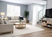 Thumbnail 2 of 26 - A living room with a grey couch, a coffee table, and a television.
