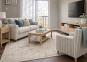 Thumbnail 1 of 14 - A living room with a couch, chair, and television.