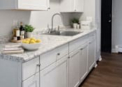 Thumbnail 2 of 10 - A kitchen with white cabinets and a marble countertop.