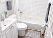 Thumbnail 8 of 10 - A white bathroom with a toilet, sink, and bathtub.