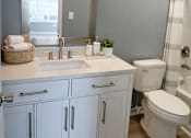 Thumbnail 13 of 27 - A bathroom with a white toilet, sink, and cabinets.
