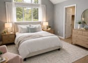 Thumbnail 11 of 26 - A bedroom with a large bed, a window with a view of trees, and a pink chair.