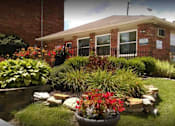 Thumbnail 8 of 14 - A well-maintained garden in front of a brick building.