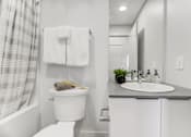 Thumbnail 4 of 16 - A white toilet sits next to a sink in a bathroom.