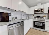 Thumbnail 5 of 16 - A modern kitchen with white cabinets and stainless steel appliances.