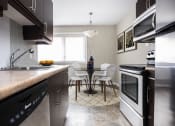 Thumbnail 7 of 15 - a kitchen with stainless steel appliances and a table and chairs