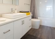 Thumbnail 15 of 18 - a bathroom with white cabinetry and a white toilet next to a white bathtub