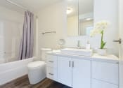 Thumbnail 14 of 18 - a bathroom with white cabinetry and a white toilet next to a white bathtub