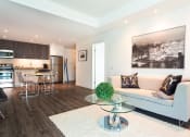Thumbnail 7 of 18 - a living room with a couch table and chairs and a kitchen in the background