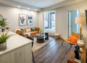 Thumbnail 9 of 30 - A living room with a white couch, a wooden coffee table, and a large window.