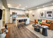 Thumbnail 4 of 30 - A modern living room with a kitchen in the background.