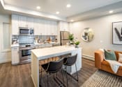 Thumbnail 5 of 30 - A modern kitchen with a white island and black chairs.