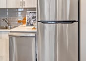 Thumbnail 17 of 30 - A stainless steel refrigerator stands next to a sink in a kitchen.