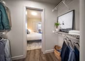 Thumbnail 21 of 30 - A bedroom with a bed, a mirror, and clothes hanging on a rack.