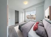 Thumbnail 1 of 30 - A bedroom with a bed, pillows, and a window overlooking a cityscape.