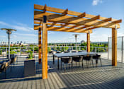 Thumbnail 26 of 30 - A wooden pergola with a table and chairs on a deck.