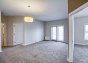 Thumbnail 28 of 31 - an empty living room with two doors and a ceiling lamp