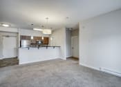Thumbnail 27 of 31 - a living area with a kitchen and a carpeted floor