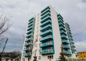 Thumbnail 21 of 21 - a tall building with green balconies and a cloudy sky