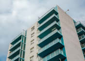 Thumbnail 19 of 21 - a tall building with balconies and a cloudy sky