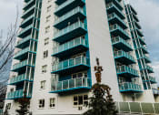 Thumbnail 18 of 21 - a tall building with green windows and a cloudy sky