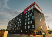 Thumbnail 4 of 18 - a tall building with a red and black sign on top of it
