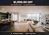 Thumbnail 1 of 19 - A modern living room with a kitchen area and a fitness center is advertised with a $1,000.00 off first month's rent offer for all 2 bedroom units.