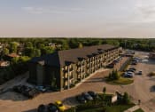 Thumbnail 5 of 31 - an aerial view of a large building with a parking lot and trees in the background