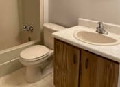 Thumbnail 4 of 6 - A white toilet sits next to a sink in a bathroom.