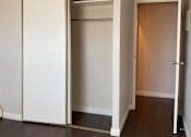 Thumbnail 3 of 6 - A white closet with a brown door is open.