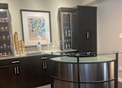 Thumbnail 3 of 15 - A modern kitchen with a curved glass island and dark wood cabinets.