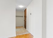 Thumbnail 17 of 21 - A hallway with a door and a light switch on the wall.