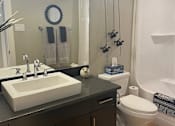 Thumbnail 10 of 15 - A bathroom with a white sink and a white toilet.