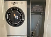 Thumbnail 11 of 15 - A white washing machine is in a small laundry room.