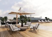 Thumbnail 1 of 7 - A patio with chairs and tables is set up on a wooden deck.