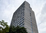 Thumbnail 2 of 31 - a tall building with many windows against a cloudy sky