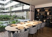 Thumbnail 6 of 7 - A modern dining room with a long table set for a meal.