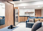 Thumbnail 8 of 12 - a living area with a sofa coffee table and a kitchen in the background