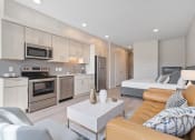 Thumbnail 50 of 59 - a living area with a couch coffee table and a kitchen with stainless steel appliances