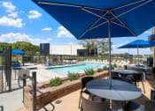 Thumbnail 31 of 59 - a patio with tables and umbrellas and a pool in the background