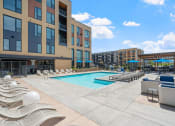 Thumbnail 34 of 59 - a swimming pool with chaise lounge chairs and umbrellas in front of a brick building