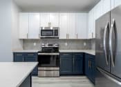Thumbnail 21 of 49 - a kitchen with blue and white cabinets and stainless steel appliances