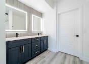 Thumbnail 23 of 49 - a bathroom with dark blue cabinets and a white door