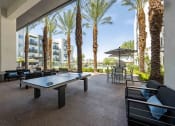 Thumbnail 39 of 49 - a patio with a ping pong table and chairs with palm trees in the background
