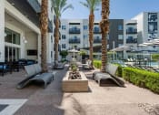 Thumbnail 40 of 49 - a patio with lounge chairs and a fire pit in front of a slate scottsdale apartment building