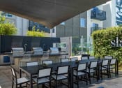 Thumbnail 12 of 49 - a long dining table with chairs in front of an outdoor kitchen