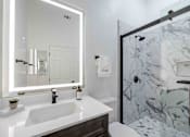 Thumbnail 39 of 63 - a bathroom with a sink and a shower and a mirror